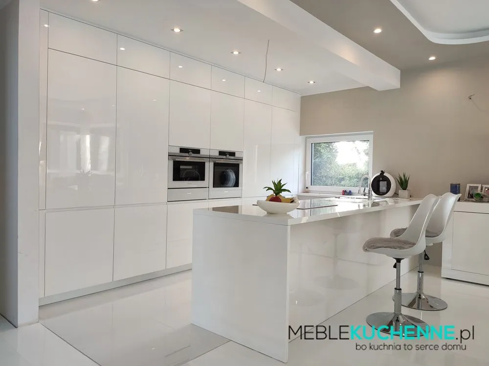 Aranżacje kuchni nowoczesnych, kuchnia z wyspą – biała zabudowa na wysoki połysk, gładkie fronty, wyspa z hokerami i oknem nad blatem