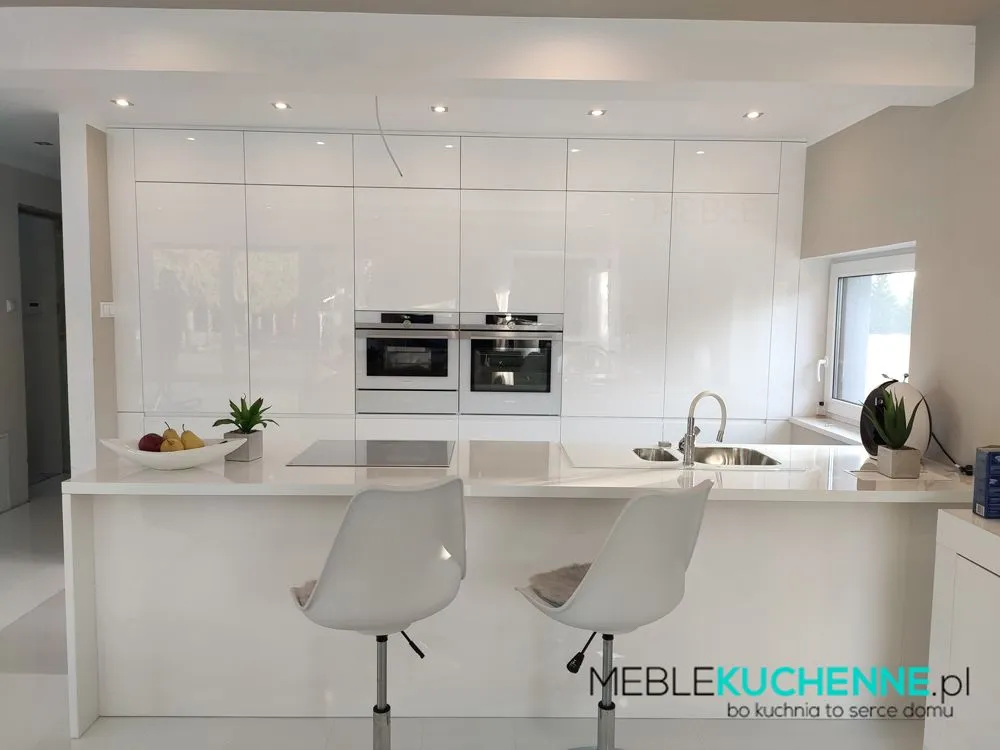 Aranżacja kuchni na wymiar – biała kuchnia z wyspą, lakierowanymi frontami na wysoki połysk, zabudową do sufitu i oknem nad blatem